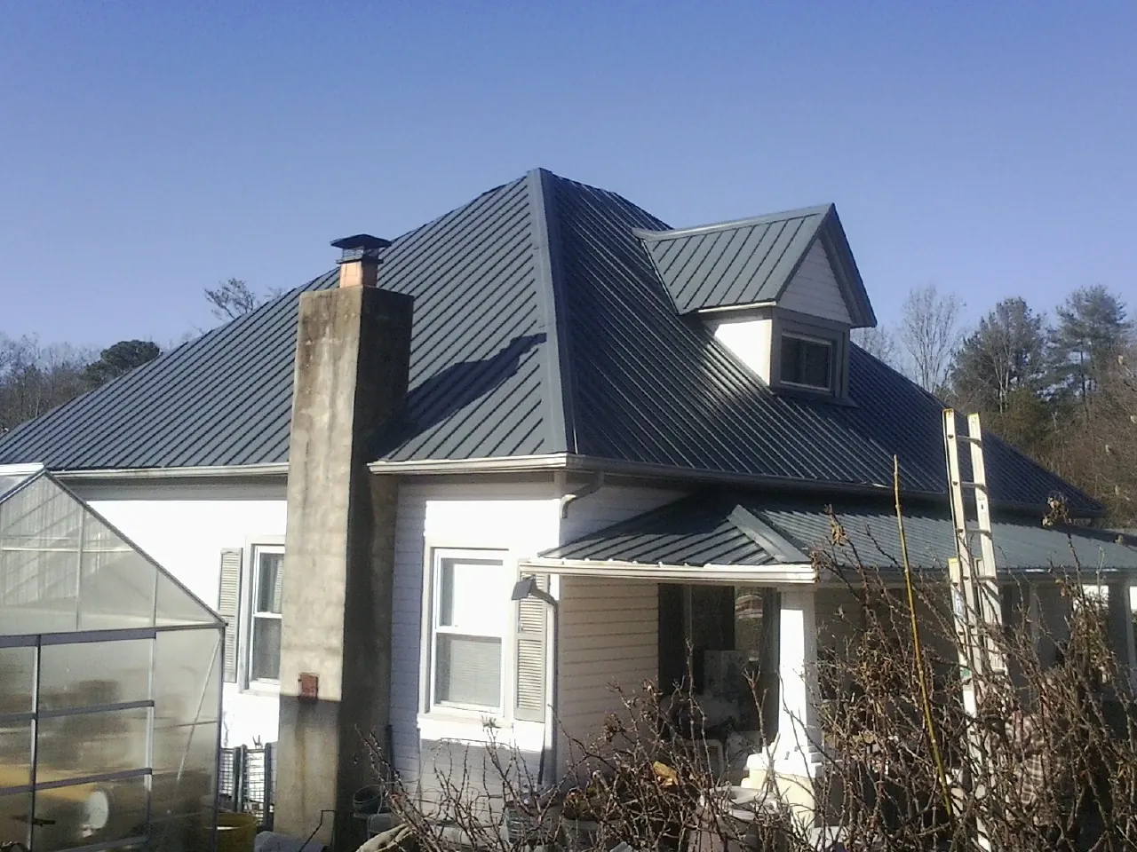 Dark blue standing seam metal roof on a white farmhouse with dormer — Slate & Tile Roof Repair by Roofing Brothers in Meridale