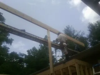 Carpenter setting a ridge beam over a new addition frame — Ice Dam Removal by Roofing Brothers in Meridale