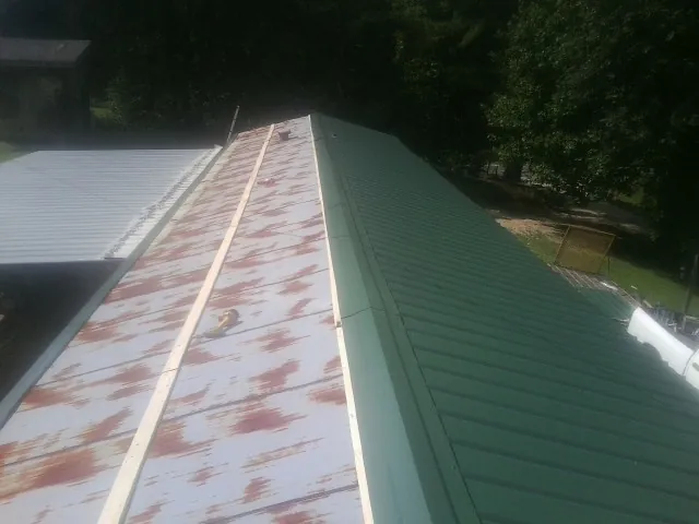 Old rusted panels beside newly installed green metal roofing — Wind Damage Roof Repair by Roofing Brothers in Meridale