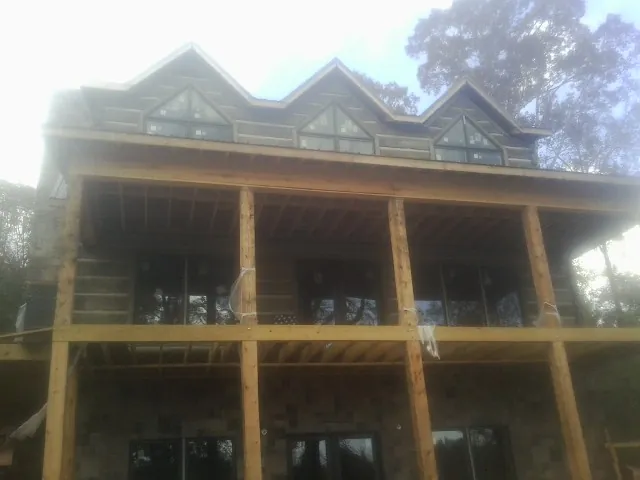 Dormers and porch framing on a large log home under construction — Roof Coating work by our crew in Meridale