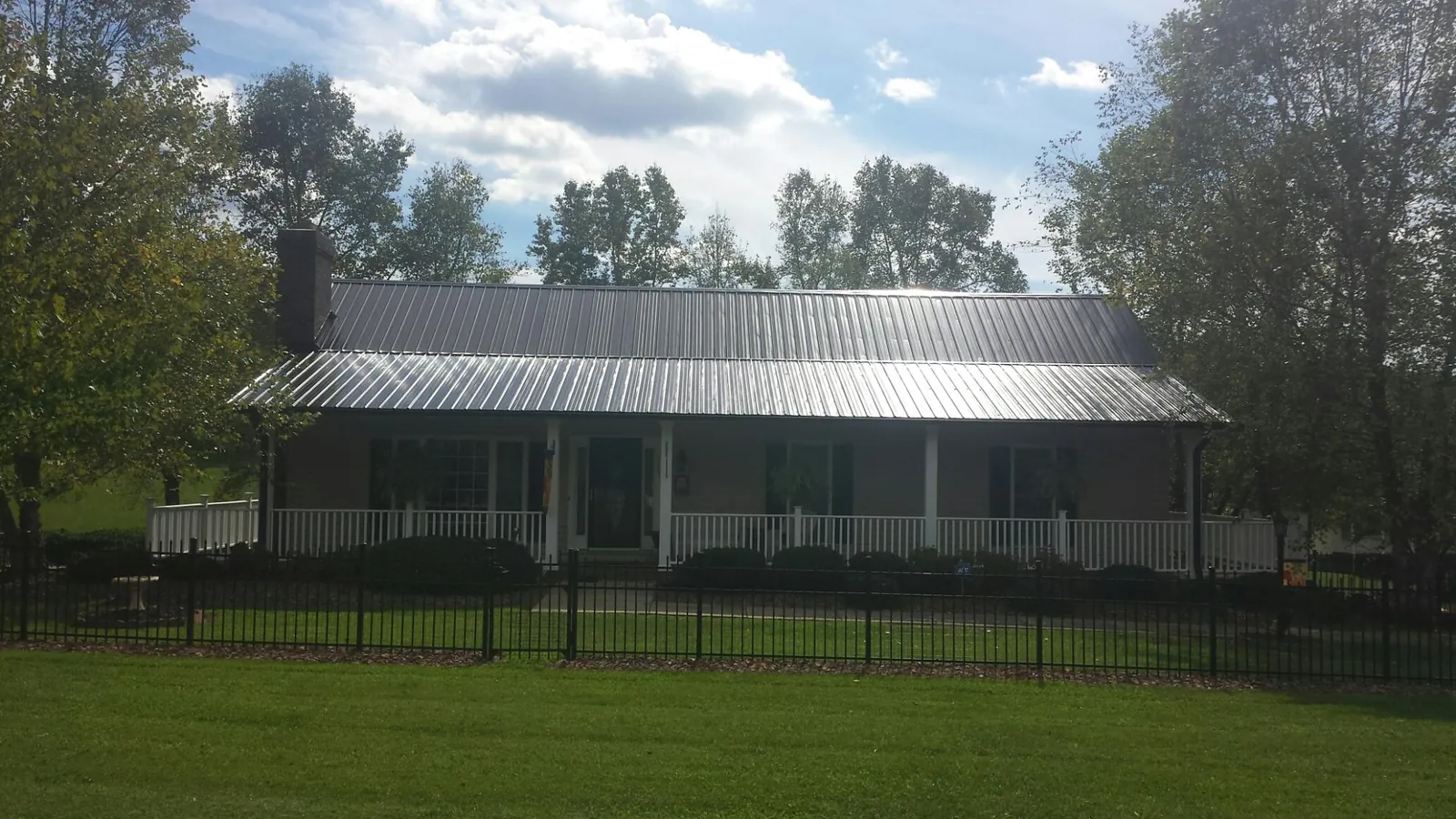 Gray metal roof on a brick ranch with a full width front porch — Gutter Guard Installation work by our crew in Meridale
