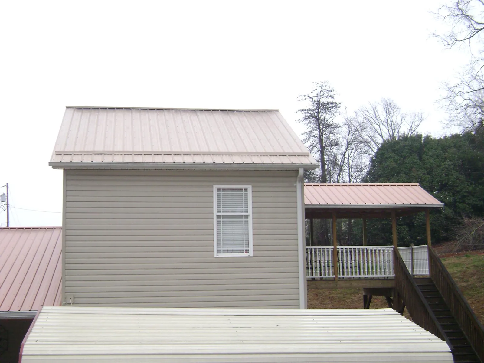 Tan metal roofs on a two story addition and attached porch, from a Roof Replacement job in Meridale