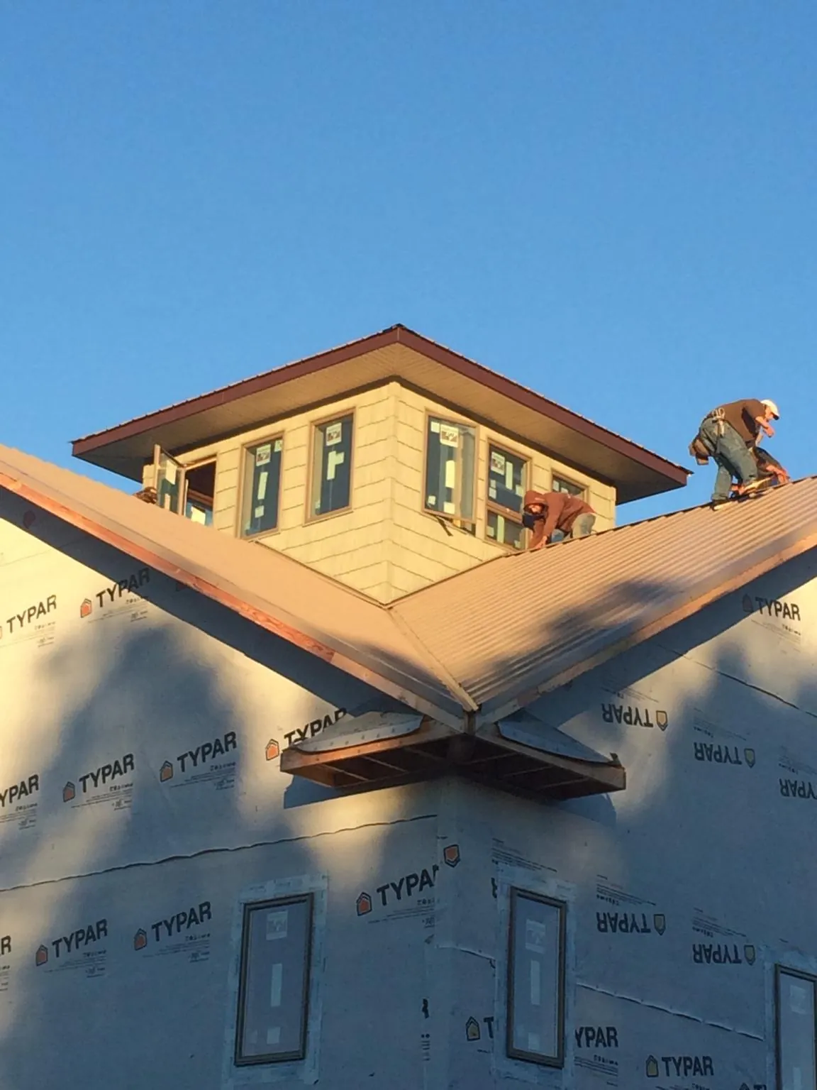 Roofers working around a rooftop cupola on a new metal roof at sunset — Roof Waterproofing in Meridale by Roofing Brothers